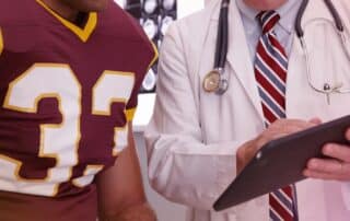 Sports medicine doctor evaluating athlete knee injury and discussing recovery and rehabilitation plan in clinic