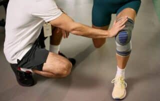 Physical therapist guiding athlete through rehabilitation exercises in sports physical therapy clinic for injury recovery